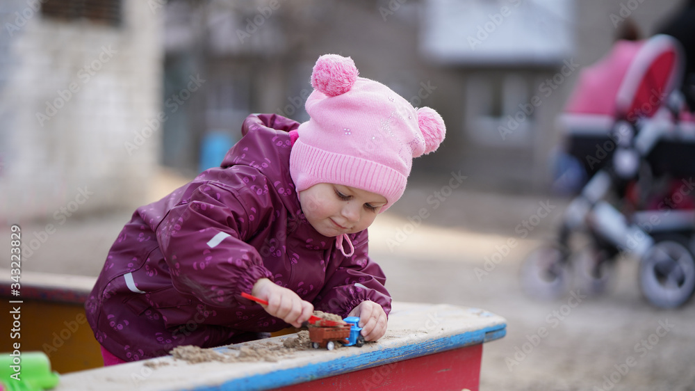 Portrait of cute little girl in pink hat with pompons on playground Portrait of cute little girl in pink hat with pompons on playground