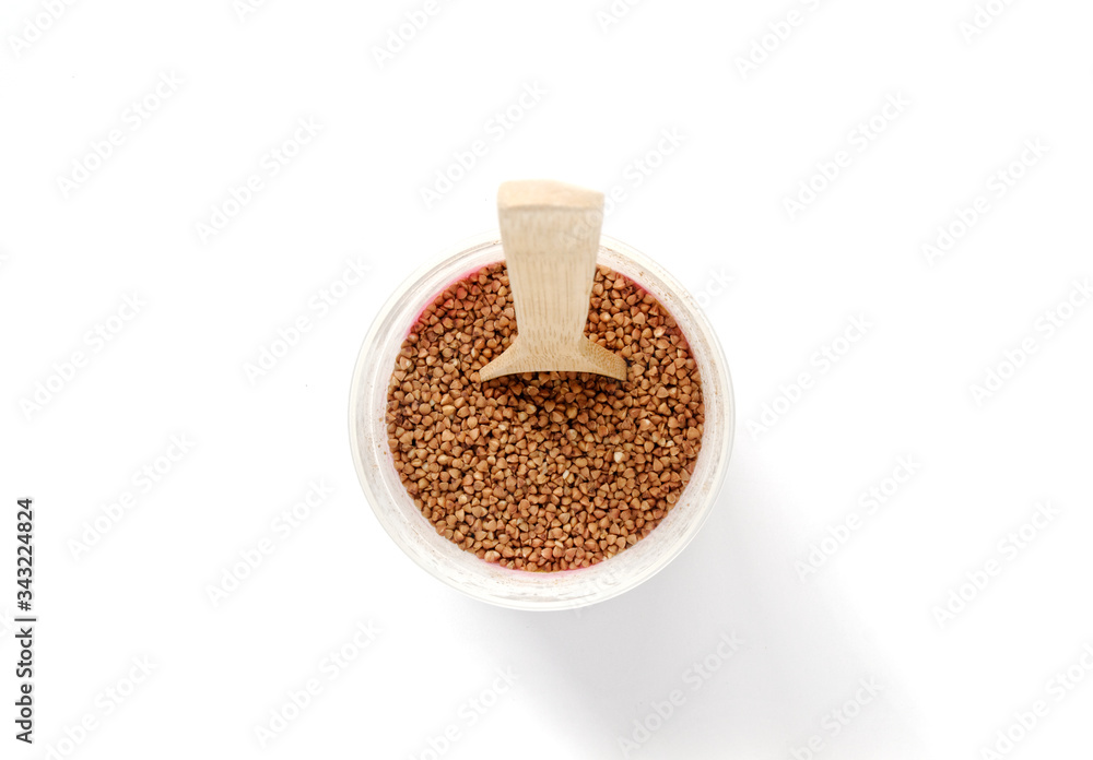 buckwheat in a plastic jar. wooden spoon in buckwheat. buckwheat in a plastic jar. wooden spoon in buckwheat.