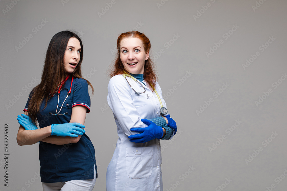 Two lovely young caucasian female in dark blue t-shirt, a white gown, white trousers with a phonendoscope have a nice job together Two lovely young caucasian female in dark blue t-shirt, a white gown, white trousers with a phonendoscope have a nice job together
