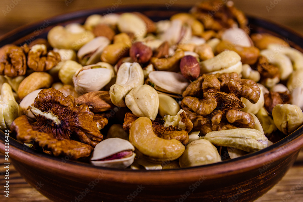 Various nuts (almond, cashew, hazelnut, pistachio, walnut) in ceramic plate on a wooden table. Vegetarian meal. Healthy eating concept Various nuts (almond, cashew, hazelnut, pistachio, walnut) in ceramic plate on a wooden table. Vegetarian meal. Healthy eating concept