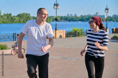 Couple of middle-aged man and woman running in park