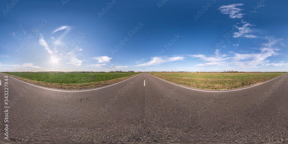 Fototapeta premium Full spherical seamless panorama 360 degrees angle view on no traffic asphalt road among fields in evening before sunset with cloudy sky. 360 panorama in equirectangular projection, VR AR content