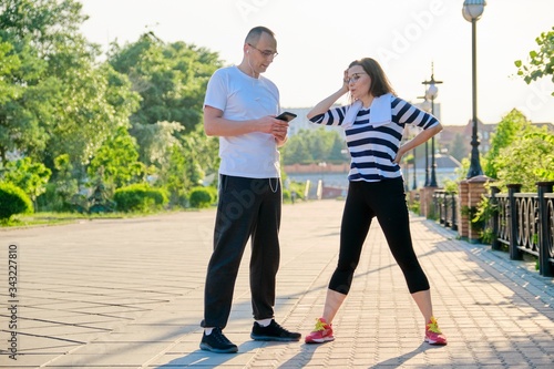 Couple of adult people resting talking after sports exercises, jogging in the park