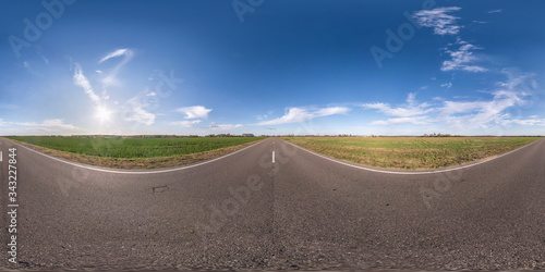 Full spherical seamless panorama 360 degrees angle view on no traffic asphalt road among fields in evening  before sunset with cloudy sky. 360 panorama in equirectangular projection  VR AR content