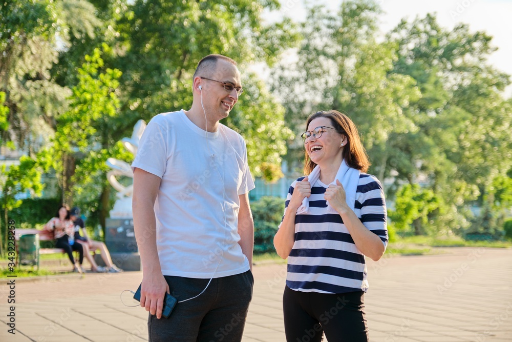 Couple of adult people resting talking after sports exercises, jogging in the park Couple of adult people resting talking after sports exercises, jogging in the park