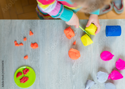 Detail of child having fun playing with colorful dough at home.