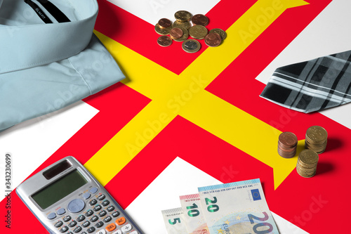 Guernsey flag on minimal money concept table. Coins and financial objects on flag surface. National economy theme. photo