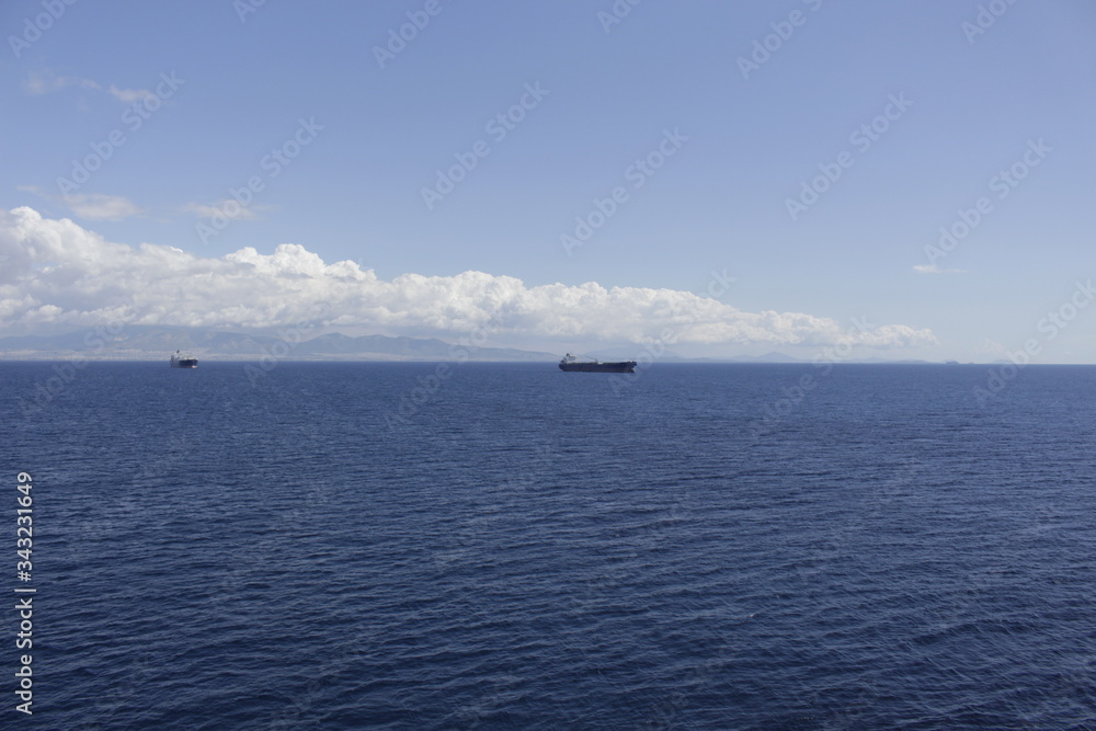 A marine ship goes into the distance against the background of islands and a blue sky.