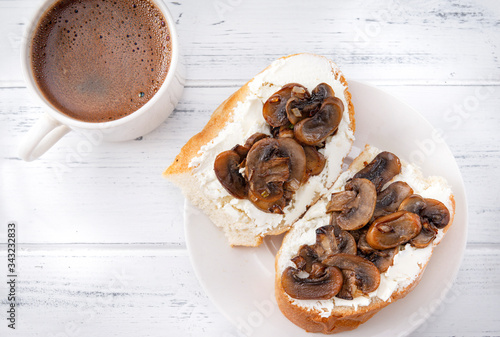 sandwiches with soft cheese and mushrooms on a plate, a Cup of black coffee on a white wooden background, Breakfast