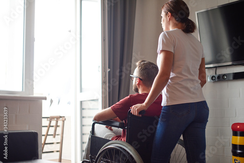 Foto Woman helping disabled man in wheelchair at home