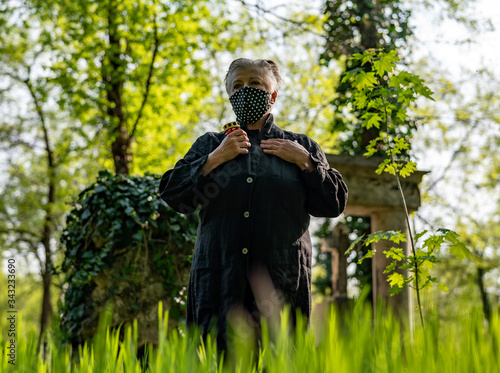 Senior woman in black dotted mask in a cemetery