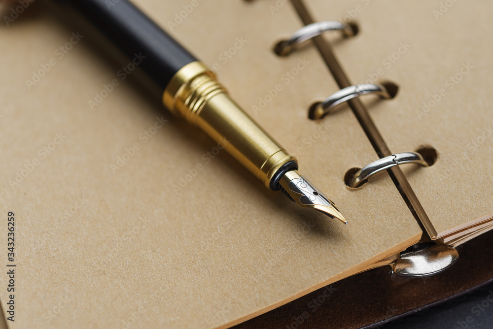 Black fountain pen on a notebook with yellow pages. Black fountain pen on a notebook with yellow pages.