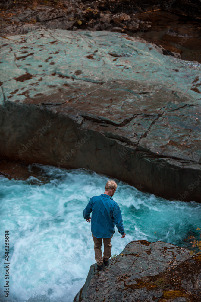 Man standing on rock over raging river in Mt. Rainier National park