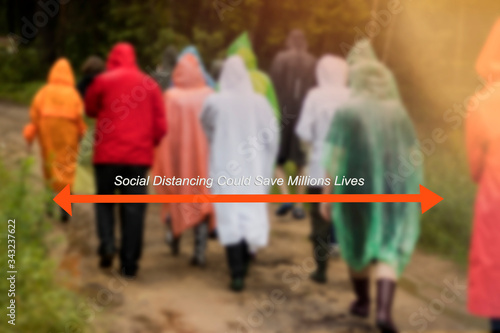 White text is on a blurred photo with unrecognizable people in color raincoats go to the forest. Social distancing could save millions of lives. covid-19 virus outbreak. photo