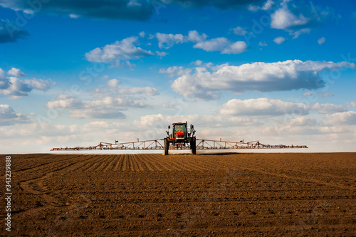 self-propelled sprayer with long arms, fertilizer spreader that fertilizes farm fields view with beautiful clouds.