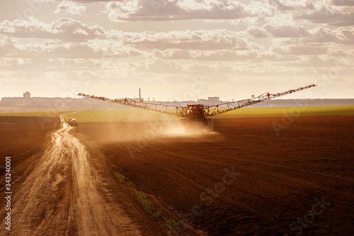 Big sprayer in the arable field with dirt road in early spring   view with evening sky sunset