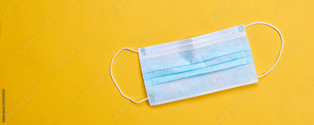 surgical face protective mask over bright yellow background. epidemic symbol concept. space for text. surgical face protective mask over bright yellow background. epidemic symbol concept. space for text.