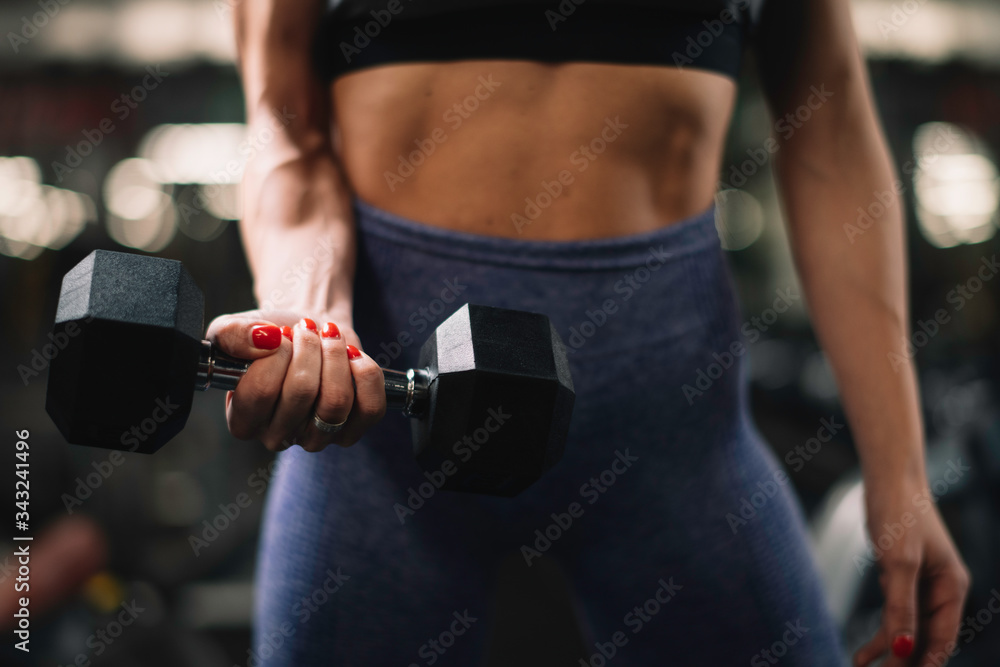 Close up of woman with dumbbells on training. Young woman in the gym.	
