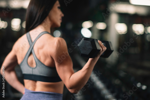 Close up of woman with dumbbells on training. Young woman in the gym. 