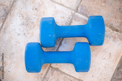 Two dumbbells isolated high angle view.Pair of blue dumbbell weights on wood board horizontal view sports training concept.