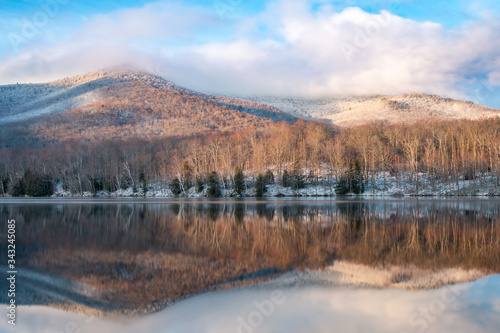 A dramatic reflection of mountains in an Adirondack lake after a spring snow storm. 