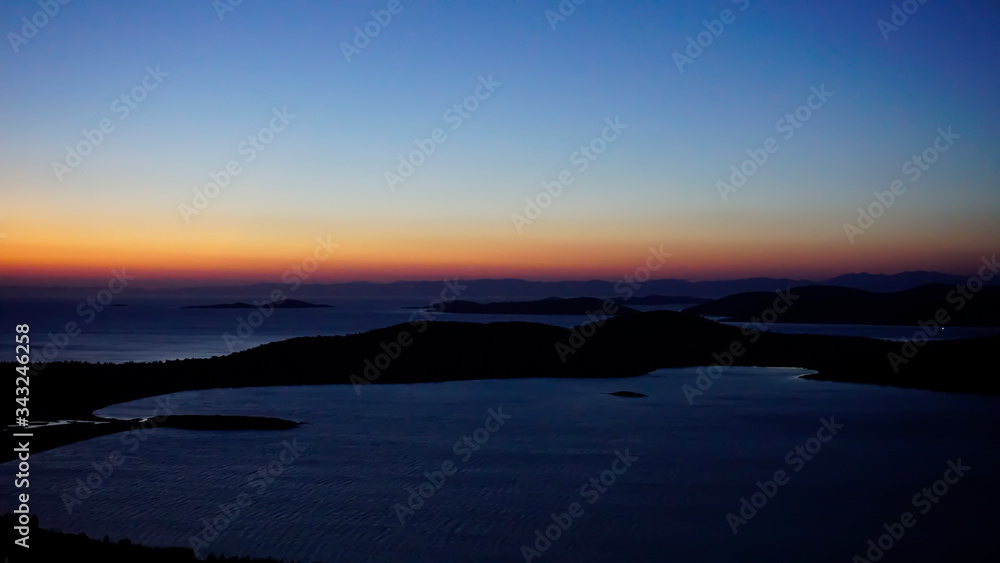 Blazing sunset over Aegean Sea (Ege Denizi) in Seytan Sofrasi (Devil's Table), Ayvalik, Turkey. Bright dramatic sky, dark ground. Scenic colorful sky at sunset landscape. Sun over skyline, horizon.	
