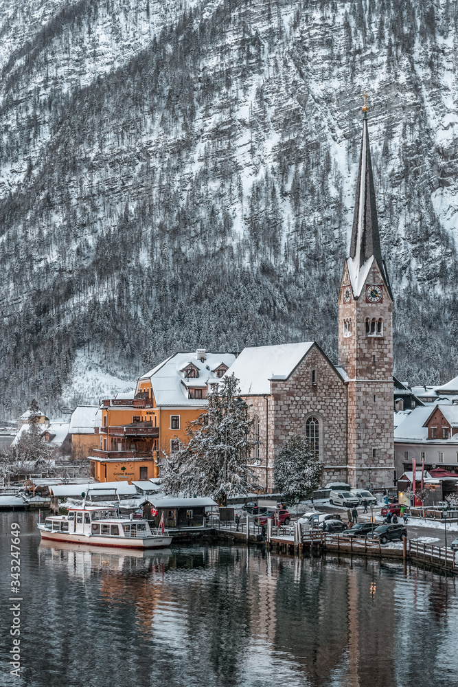 Snowy village Hallstatt by lake at foot of snow mountain with clear sky in winter in Austria