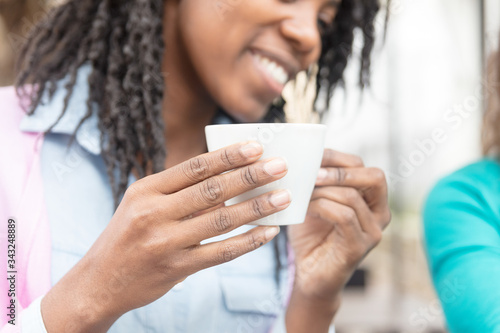 Fototapeta Naklejka Na Ścianę i Meble -  Young African woman drinking a cup of coffee