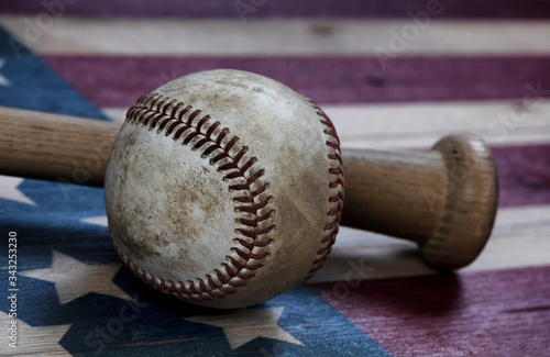 Closeup view of a used baseball and traditional wood bat on rustic wooden United States Flag