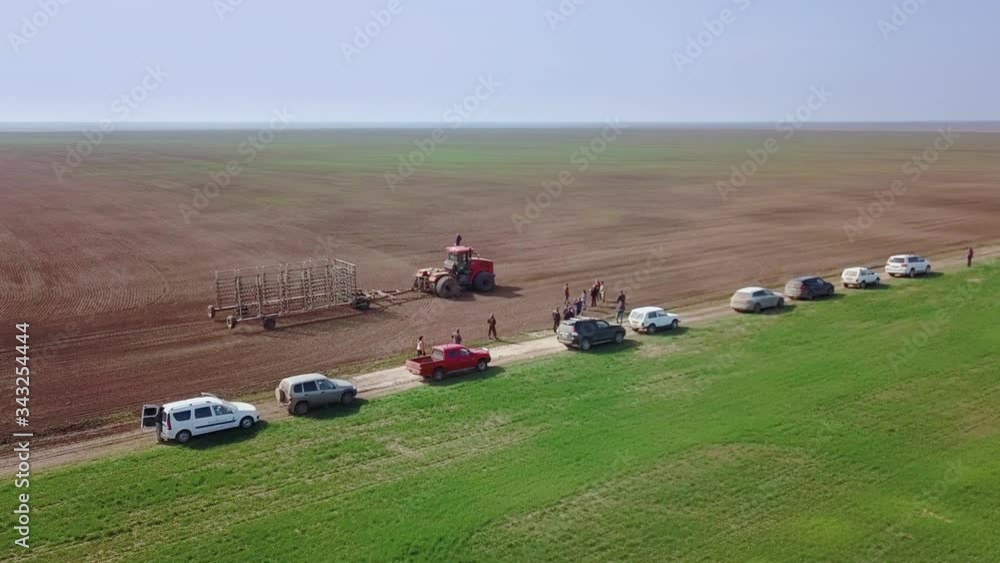 Farmer in a tractor with a seeder prepares the land for sowing grain crops in ploughed field. Planting seeds in dust ground. Spring agricultural work. Aerial top view, drone fly forward follow tractor Farmer in a tractor with a seeder prepares the land for sowing grain crops in ploughed field. Planting seeds in dust ground. Spring agricultural work. Aerial top view, drone fly forward follow tractor