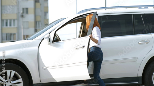 Yong pretty woman standing near a big all terrain car outdoors. Driver girl in casual clothes outside her vehicle.