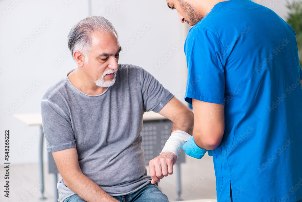 Obraz premium Young male doctor and old patient in first aid concept