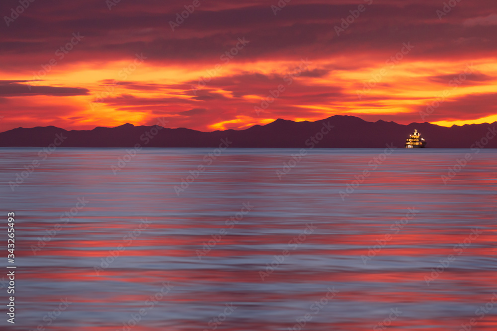 Yach on sunrise with background of dramatic red sky Yach on sunrise with background of dramatic red sky