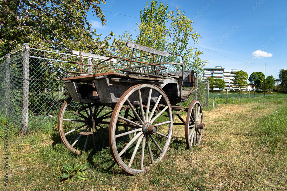 DALLIKON, SWITZERLAND - APRIL 18, 2020: An old wooden vintage carriage from old times stands in front of a farm by the road