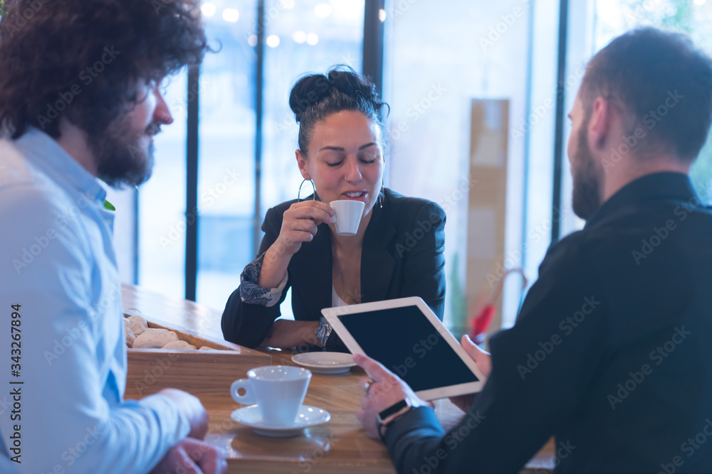 Obraz premium Young business people talking with each other about new projects at a coffee bar