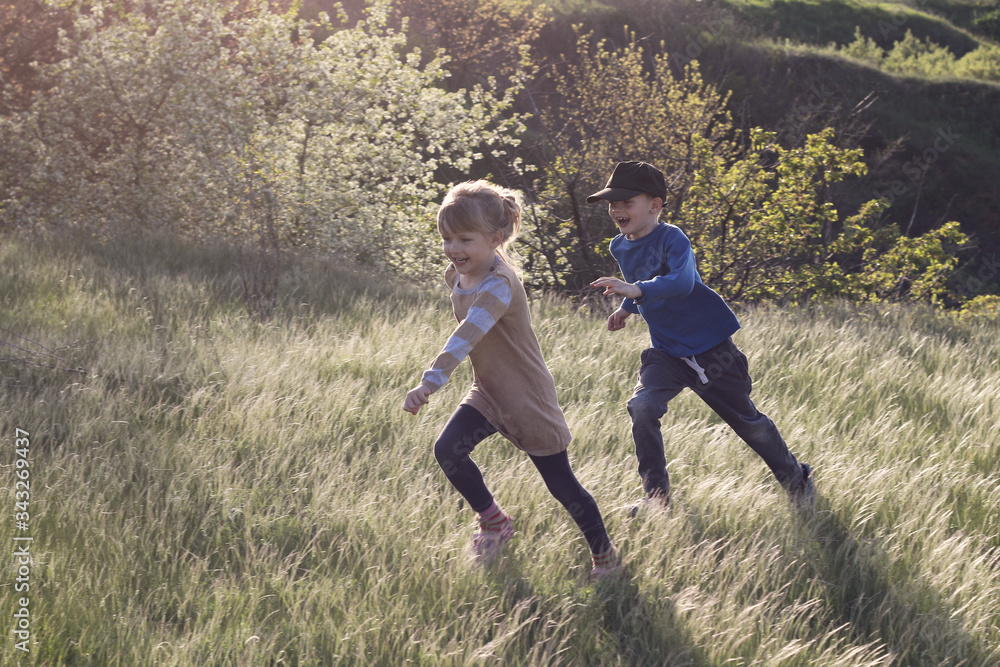 Little happy children run and play in the tall beautiful grass. Little happy children run and play in the tall beautiful grass.