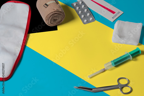 Bahamas flag with first aid medical kit on wooden table background. National healthcare system concept, medical theme.