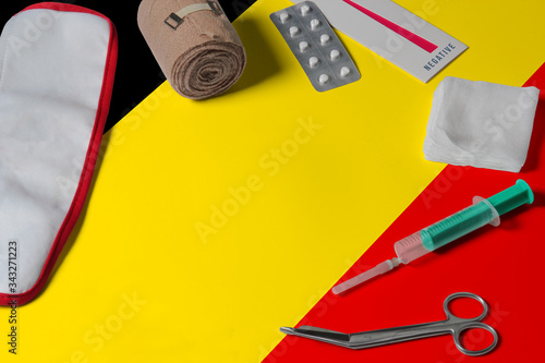 Belgium flag with first aid medical kit on wooden table background. National healthcare system concept, medical theme.