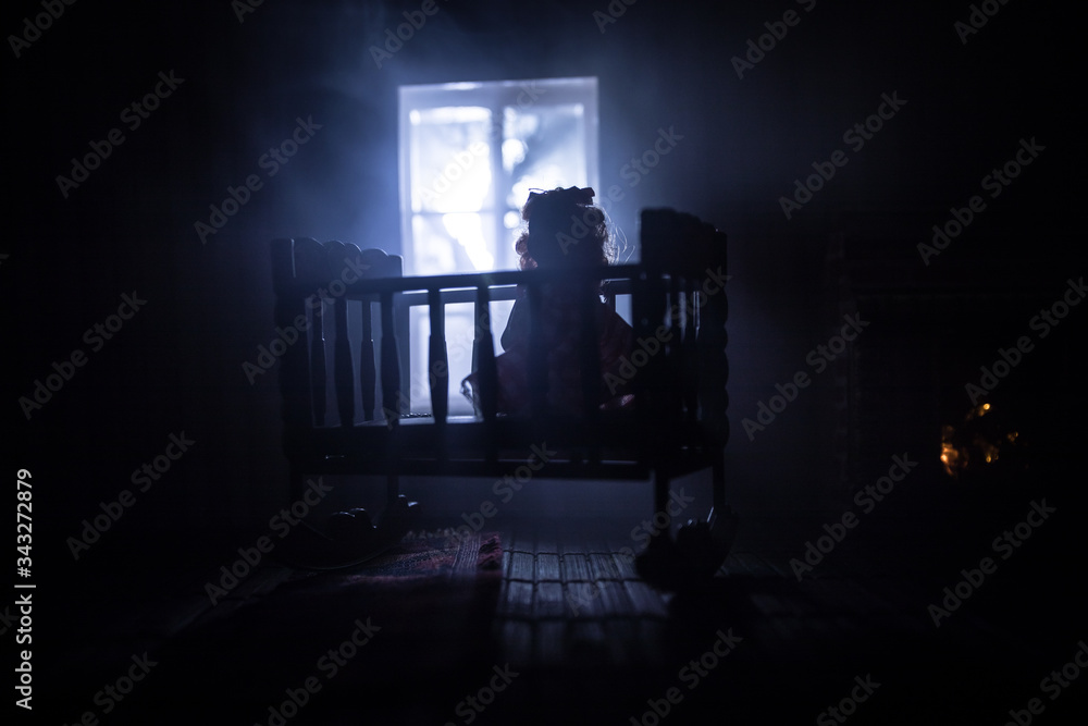 Old creepy eerie baby crib near window in dark room. Scary baby
