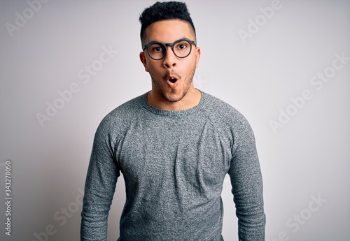 Young handsome man wearing casual sweater and glasses over isolated white background afraid and shocked with surprise expression, fear and excited face. © Krakenimages.com