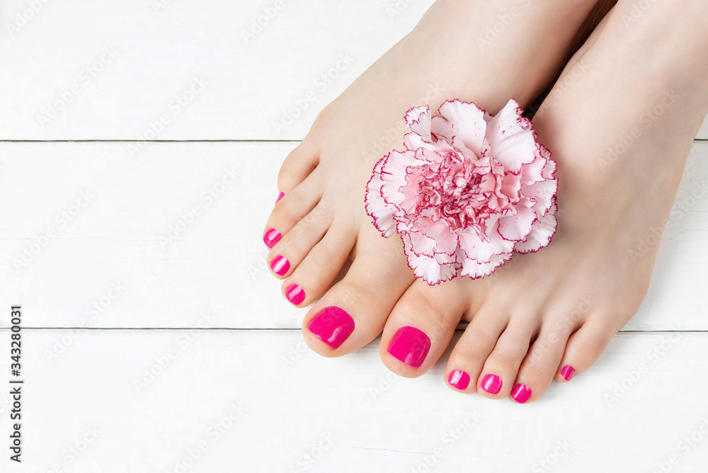 Pink pedicure with a flower on white wooden background, top view, copy space