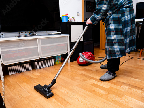 Man vacuuming the living room of a home with the wooden floor during alertness