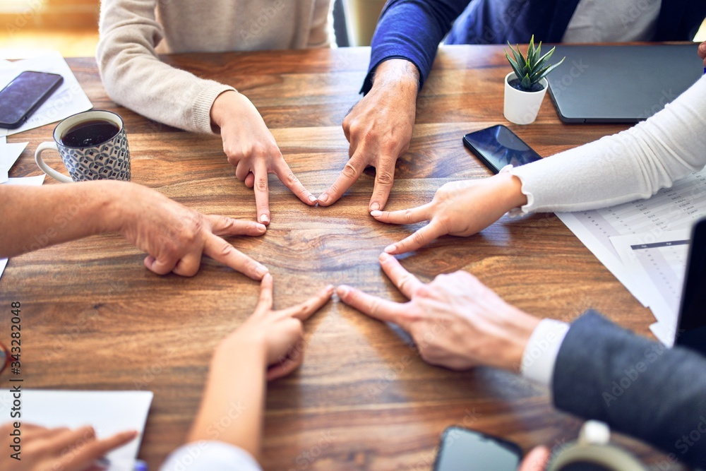 Group of business workers standing with hands together. Doing symbol with fingers at the office Group of business workers standing with hands together. Doing symbol with fingers at the office