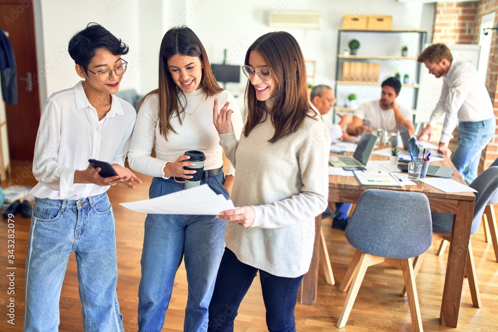 Obraz premium Beautiful businesswomen smiling happy. Standing with smile on face working together reading documents using smartphone at the office