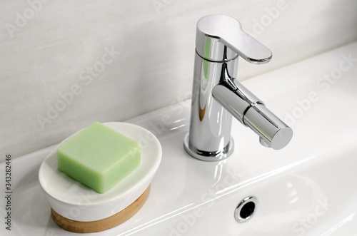 Fotografi Soap in a soap dish on a white sink in the bathroom next to a chrome faucet