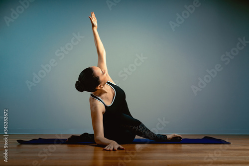 Athletic aged woman doing yoga on a blue background - the concept of a healthy lifestyle and a natural balance between the body and mental development and aging. Active old age.