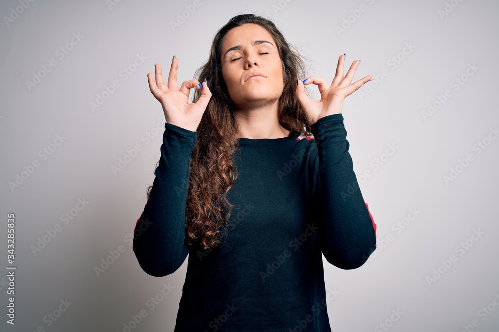 Young beautiful woman with curly hair wearing casual sweater over isolated white background relax and smiling with eyes closed doing meditation gesture with fingers. Yoga concept. Young beautiful woman with curly hair wearing casual sweater over isolated white background relax and smiling with eyes closed doing meditation gesture with fingers. Yoga concept.