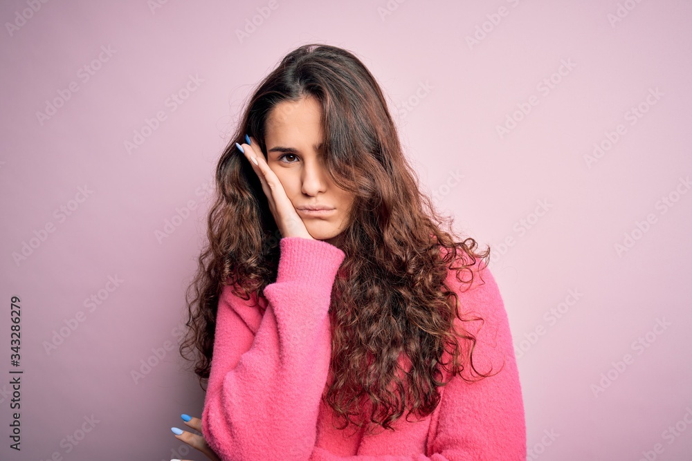 Young beautiful woman with curly hair wearing casual sweater over isolated pink background thinking looking tired and bored with depression problems with crossed arms. Young beautiful woman with curly hair wearing casual sweater over isolated pink background thinking looking tired and bored with depression problems with crossed arms.