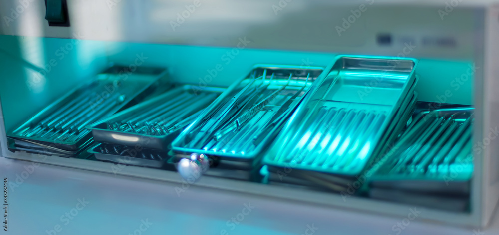 Sterilization of instrument with ultraviolet lamp in dental clinic. Closeup different medical  instruments and accessories inside ultraviolt steriliser. Medical instruments sterilized under UV.
