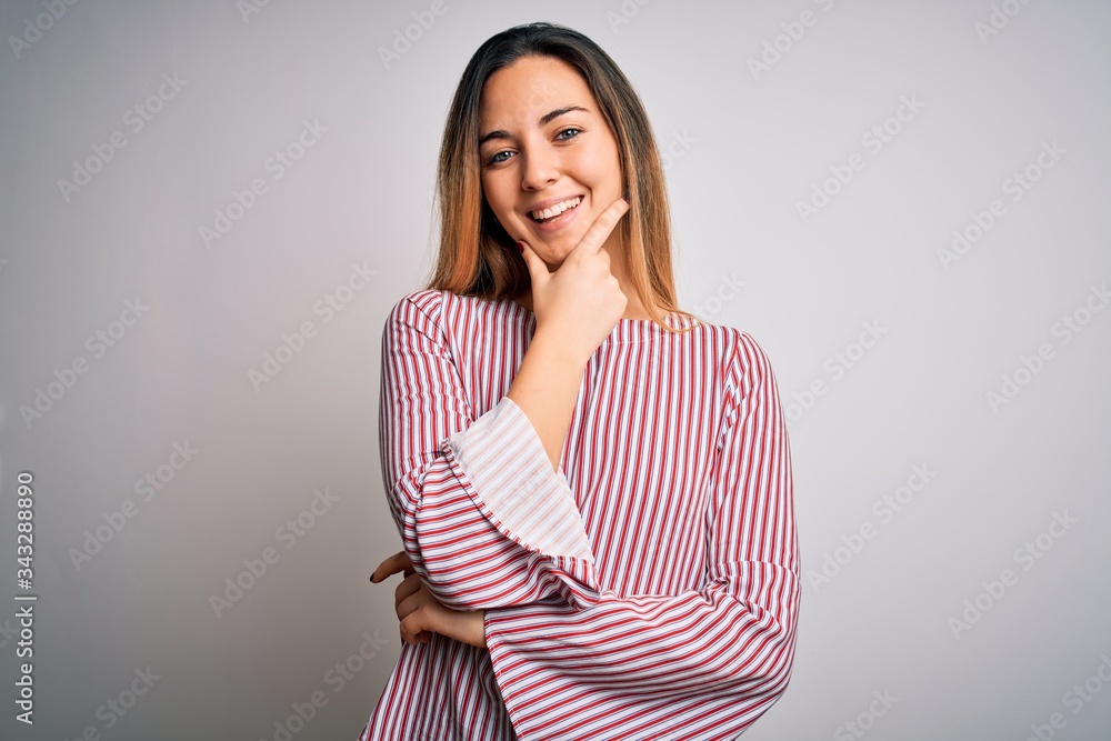 Young beautiful blonde woman with blue eyes wearing stiped t-shirt over white background looking confident at the camera smiling with crossed arms and hand raised on chin. Thinking positive. Young beautiful blonde woman with blue eyes wearing stiped t-shirt over white background looking confident at the camera smiling with crossed arms and hand raised on chin. Thinking positive.